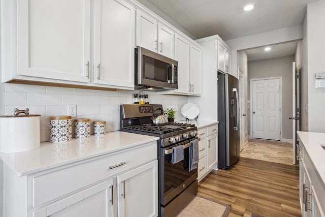 kitchen with stainless steel appliances, white cabinetry, light countertops, light wood-style flooring, and tasteful backsplash