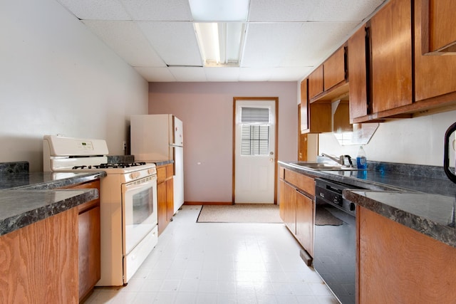 624 Main St, West Concord, MN 55985 - kitchen featuring white appliances, a paneled ceiling, dark countertops, a sink, and brown cabinetry