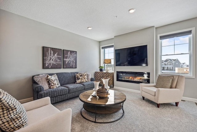 carpeted living area with baseboards, a glass covered fireplace, and recessed lighting