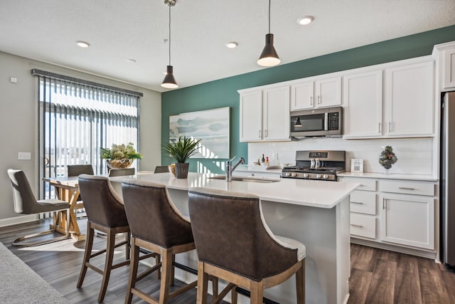 kitchen featuring appliances with stainless steel finishes, a sink, tasteful backsplash, dark wood-style flooring, and recessed lighting