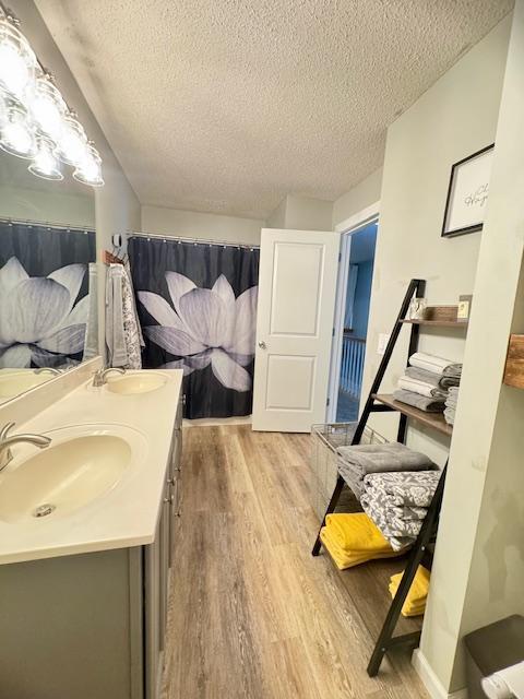 bathroom with wood finished floors, a textured ceiling, and double vanity