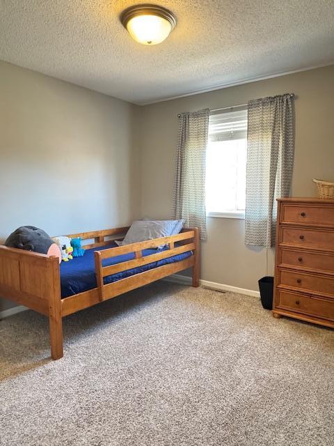 carpeted bedroom featuring a textured ceiling and baseboards