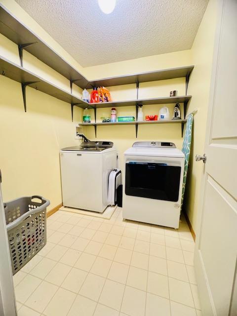 laundry area with washing machine and dryer, a textured ceiling, and baseboards