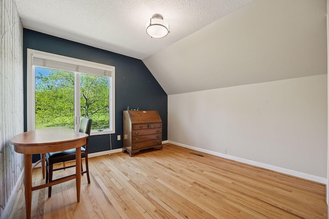 5510 Heather Dr SW, Rochester Twp, MN 55902 - dining space with light wood finished floors, vaulted ceiling, baseboards, and a textured ceiling
