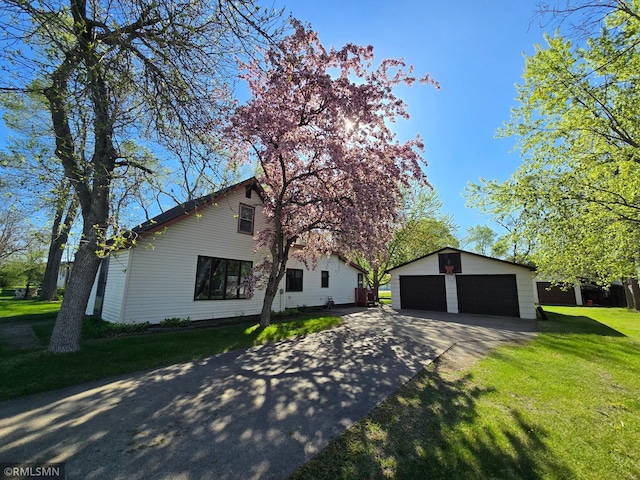 view of front of house featuring an outdoor structure, a front yard, and concrete driveway