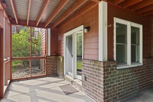 view of side of home with brick siding, covered porch, and central AC