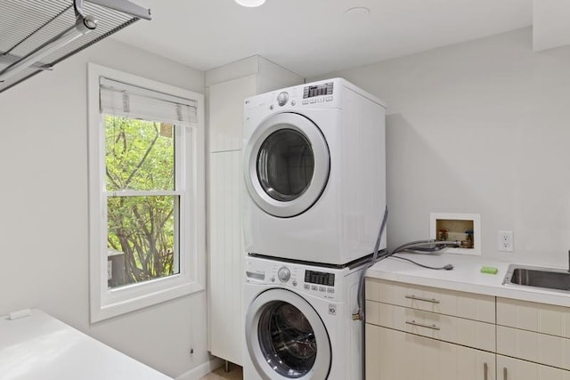 clothes washing area with estacked washer and dryer and cabinet space