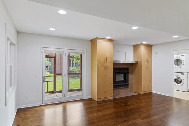unfurnished living room with estacked washer and dryer, dark wood finished floors, baseboards, and recessed lighting