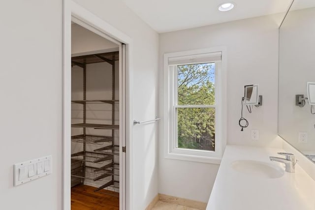 bathroom featuring baseboards, recessed lighting, and vanity