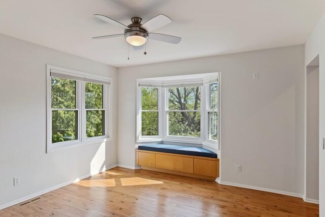 empty room with light wood-style flooring, ceiling fan, and baseboards