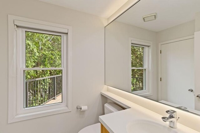 bathroom featuring healthy amount of natural light, toilet, and vanity