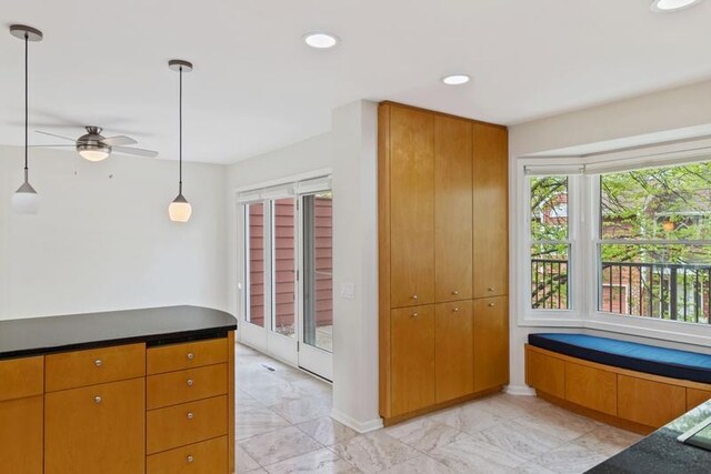 kitchen featuring light marble finish flooring, a ceiling fan, dark countertops, recessed lighting, and pendant lighting