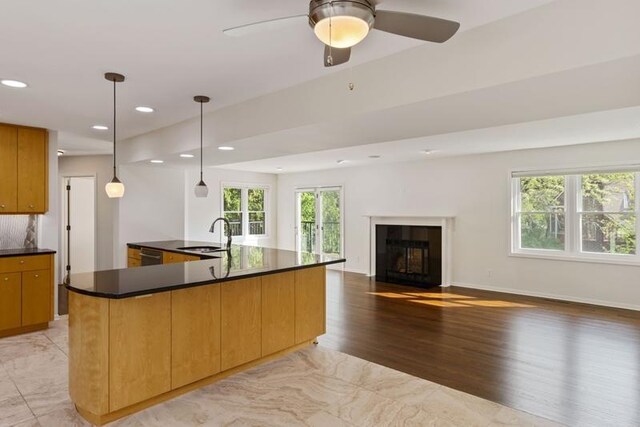 kitchen featuring a sink, dark countertops, recessed lighting, a fireplace with flush hearth, and open floor plan
