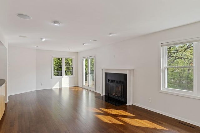 unfurnished living room with dark wood-style flooring, baseboards, and a fireplace with flush hearth