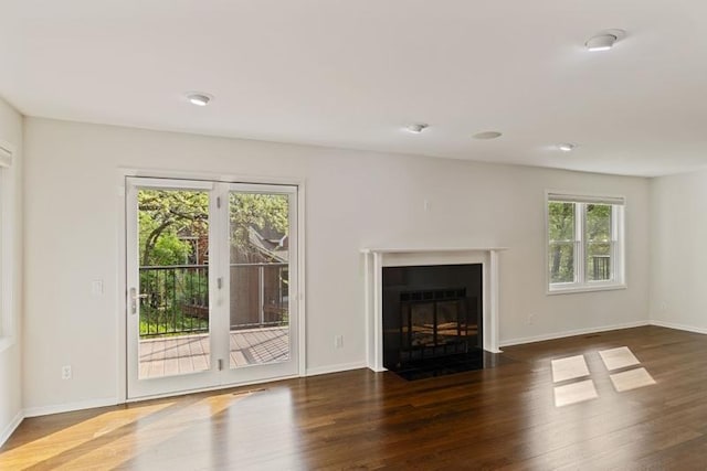 unfurnished living room with wood finished floors, a fireplace with flush hearth, and baseboards
