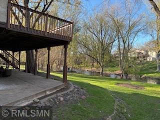 view of green lawn featuring a deck and stairs