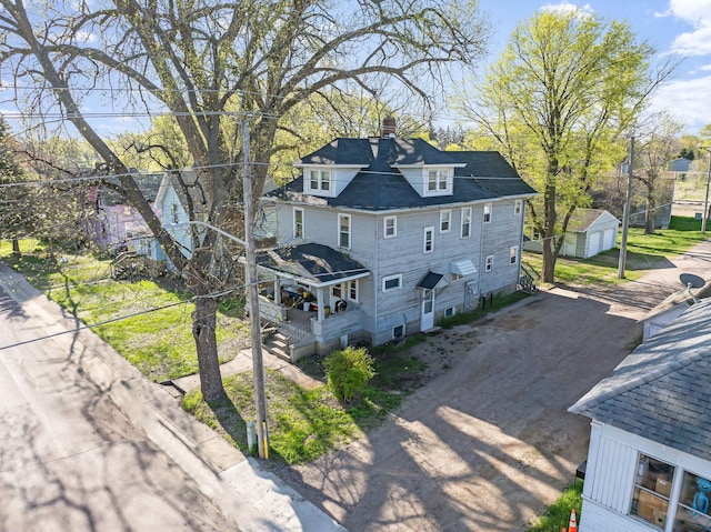 view of property exterior featuring a chimney, driveway, an outdoor structure, a porch, and a shed