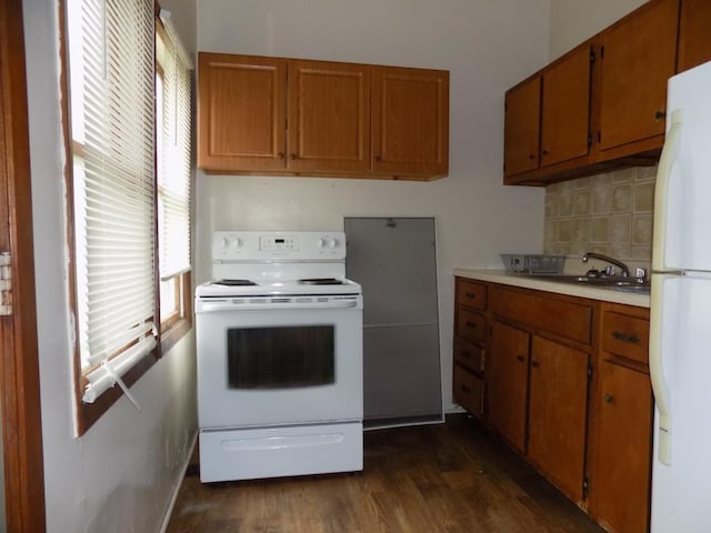 kitchen with white appliances, a sink, and brown cabinetry