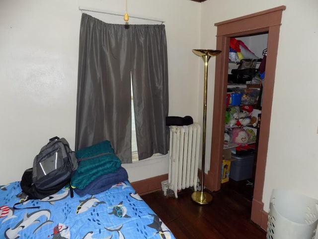 bedroom with radiator and wood finished floors