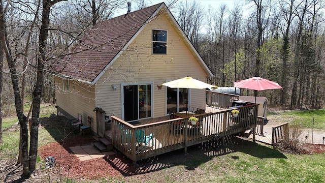 25185 Moreau Rd, Aitkin, MN 56431 - back of house with a wooden deck, roof with shingles, a view of trees, and a lawn