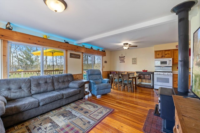 25185 Moreau Rd, Aitkin, MN 56431 - living area with a wood stove, wood finished floors, beamed ceiling, ceiling fan, and wainscoting