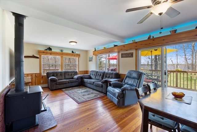 25185 Moreau Rd, Aitkin, MN 56431 - living area featuring a wood stove, wainscoting, hardwood / wood-style floors, a ceiling fan, and wood walls