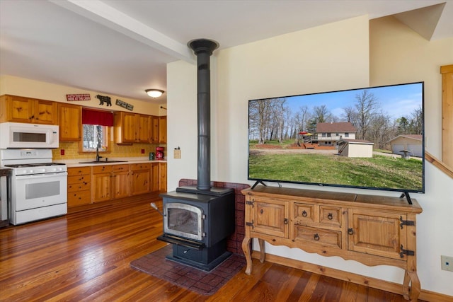 25185 Moreau Rd, Aitkin, MN 56431 - kitchen with white appliances, a wood stove, a sink, and dark wood finished floors