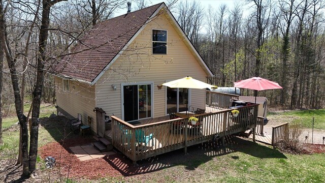25185 Moreau Rd, Aitkin, MN 56431 - back of property with a wooden deck, roof with shingles, a wooded view, and a lawn
