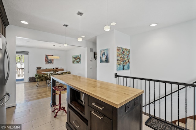 kitchen with wood counters, pendant lighting, a kitchen island, recessed lighting, and appliances with stainless steel finishes