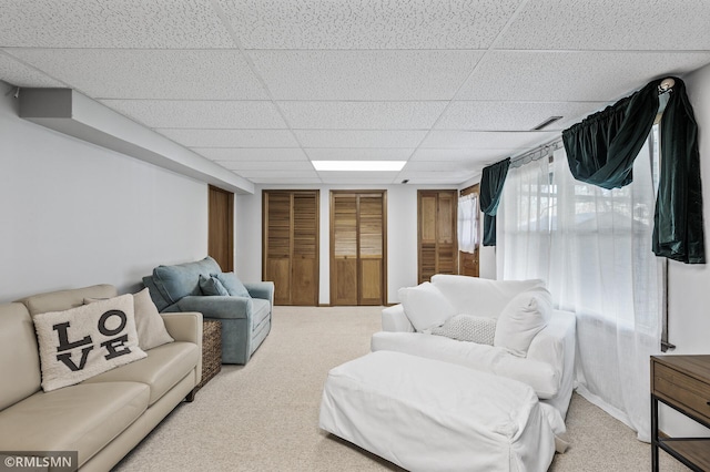 carpeted living area featuring a paneled ceiling