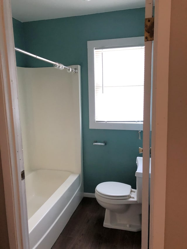 55715 State Highway 11, Warroad, MN 56763 - bathroom featuring toilet, wood finished floors, baseboards, and shower / tub combination