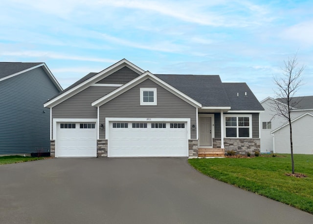 craftsman house featuring stone siding, asphalt driveway, a front lawn, and a garage
