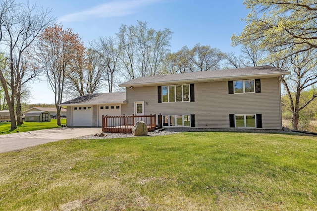 tri-level home featuring an attached garage, concrete driveway, a front lawn, and a wooden deck