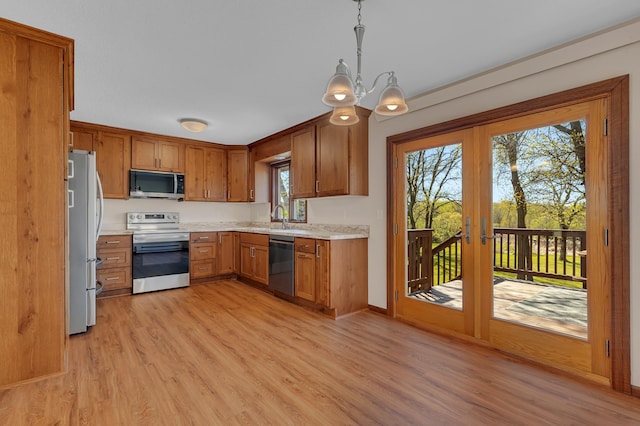 kitchen featuring appliances with stainless steel finishes, light wood finished floors, brown cabinets, and a sink