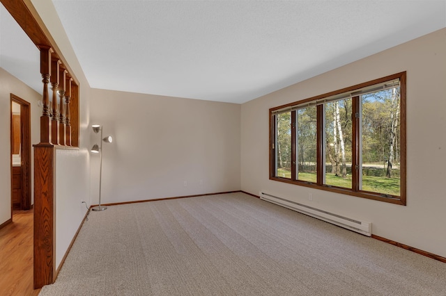 empty room featuring a baseboard heating unit, light carpet, and baseboards