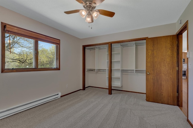 unfurnished bedroom with a baseboard heating unit, two closets, light colored carpet, and baseboards