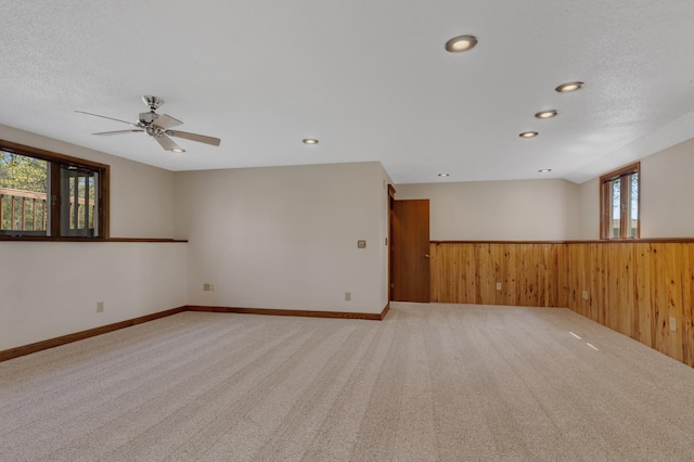 carpeted spare room with wooden walls, wainscoting, recessed lighting, and ceiling fan