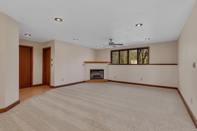 unfurnished living room with light carpet, ceiling fan, baseboards, a fireplace with raised hearth, and recessed lighting