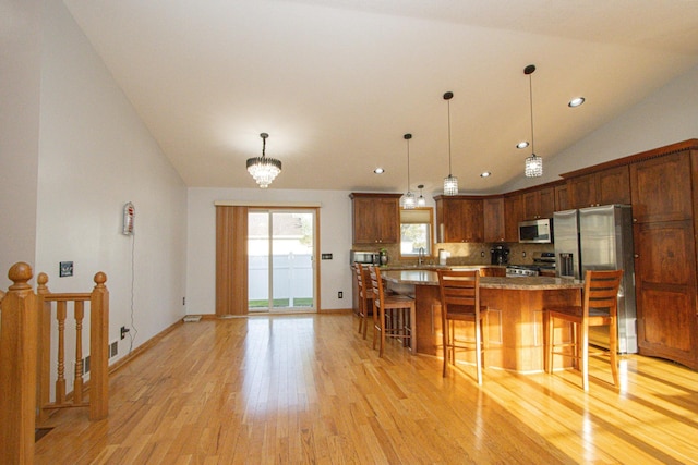 147 Waynesborough Way, Mankato, MN 56001 - kitchen with appliances with stainless steel finishes, light wood finished floors, lofted ceiling, a kitchen island, and a kitchen breakfast bar