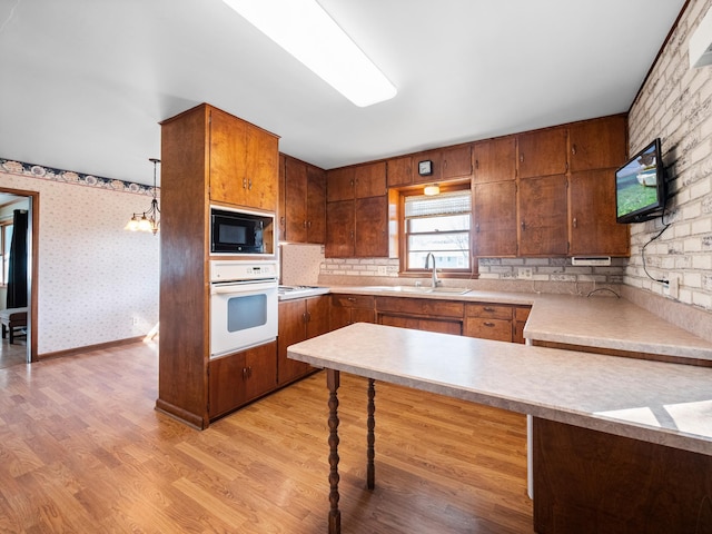 116 California Ave, Morris, MN 56267 - kitchen featuring white oven, a sink, black microwave, light wood finished floors, and brown cabinets