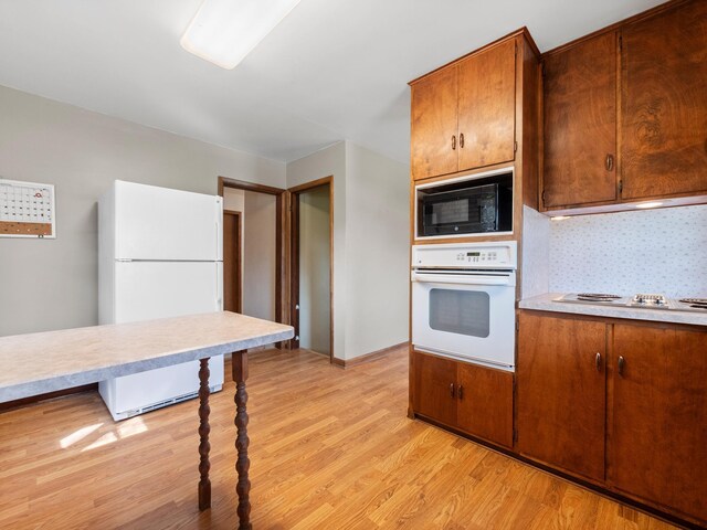 116 California Ave, Morris, MN 56267 - kitchen featuring white appliances, light countertops, brown cabinets, and light wood-style floors