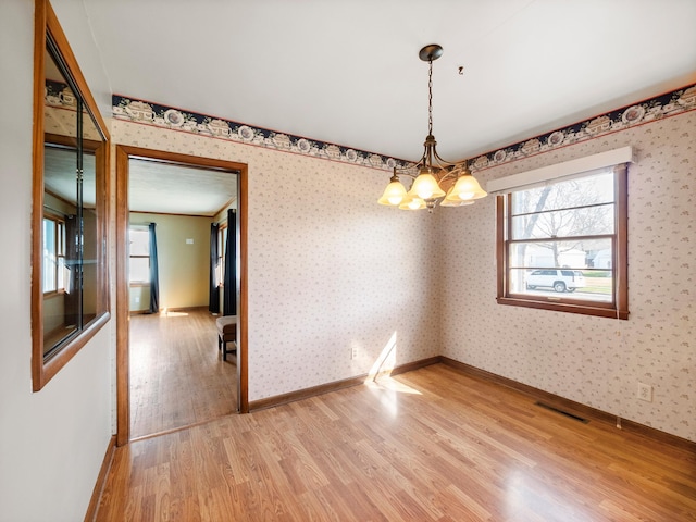 116 California Ave, Morris, MN 56267 - empty room with light wood finished floors, a chandelier, plenty of natural light, baseboards, and wallpapered walls