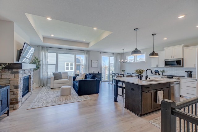 kitchen with a sink, stainless steel appliances, open floor plan, a kitchen breakfast bar, and light wood finished floors