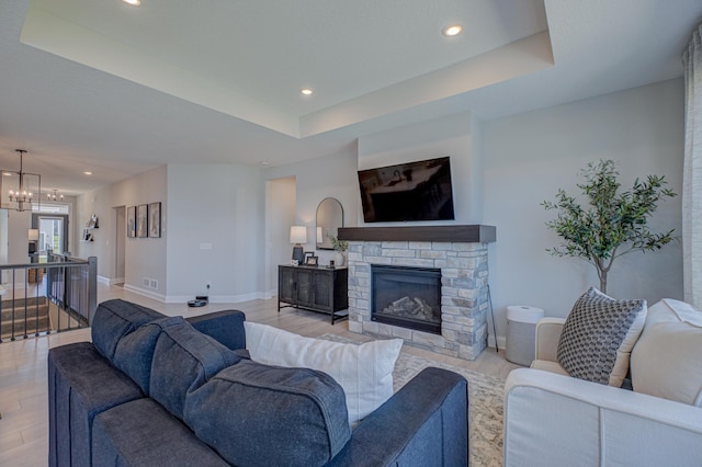 living area with light wood-style floors, a raised ceiling, recessed lighting, a chandelier, and baseboards