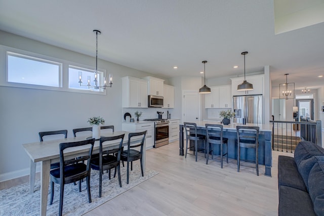 dining space with a chandelier, light wood-style floors, and recessed lighting
