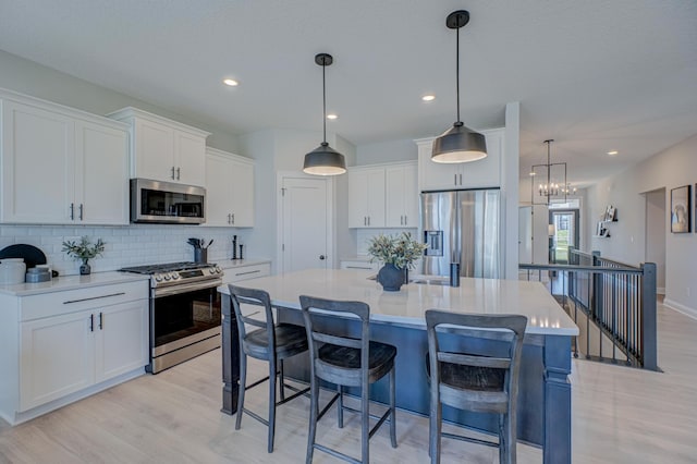 kitchen featuring appliances with stainless steel finishes, light wood-style floors, backsplash, white cabinetry, and recessed lighting