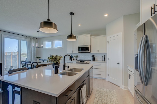 kitchen featuring appliances with stainless steel finishes, a sink, light countertops, decorative backsplash, and white cabinetry