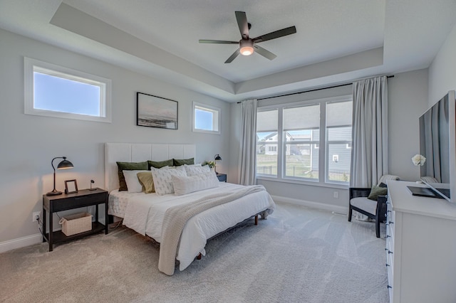 bedroom with light carpet, baseboards, and a tray ceiling