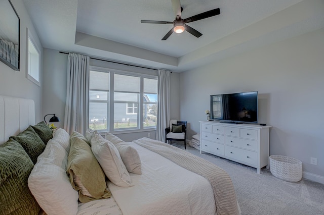 bedroom featuring light colored carpet, a ceiling fan, a raised ceiling, and baseboards