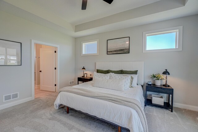 carpeted bedroom with baseboards, ceiling fan, and a raised ceiling
